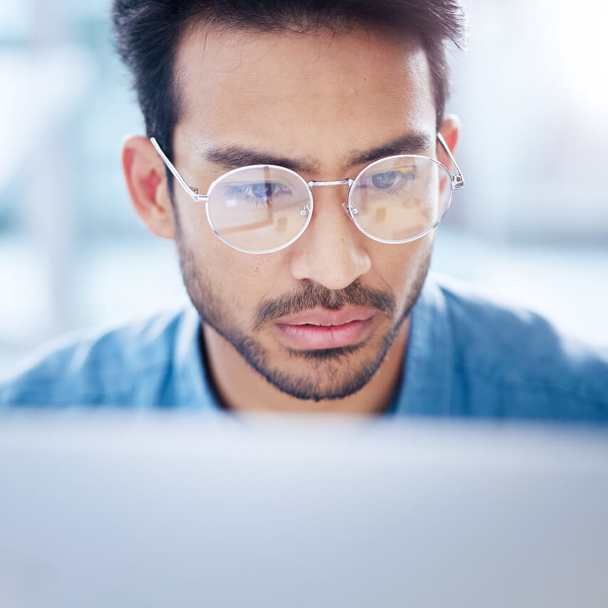 Konzentrierter Mann mit Brille vor einem Laptop.