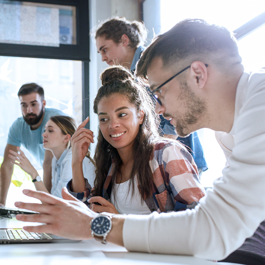 Mitarbeitende diskutieren ein Thema am Schreibtisch.